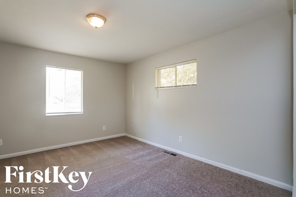 a room with a carpeted floor and two windows