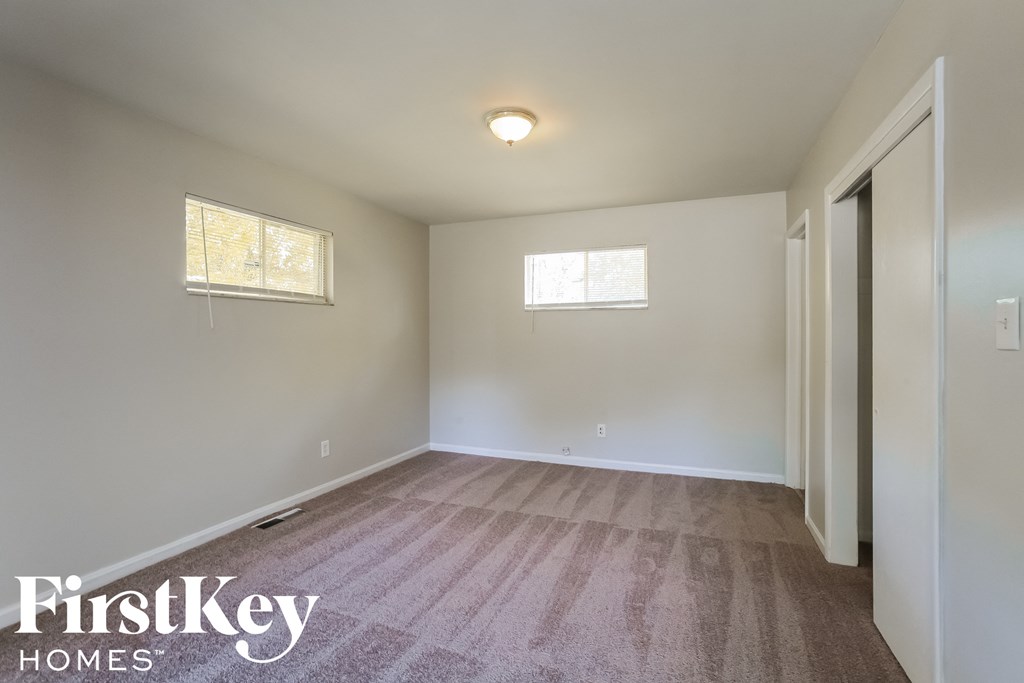 a white room with a carpet and two windows