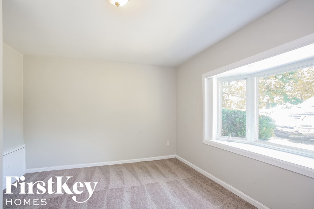 an empty bedroom with a large window and white walls