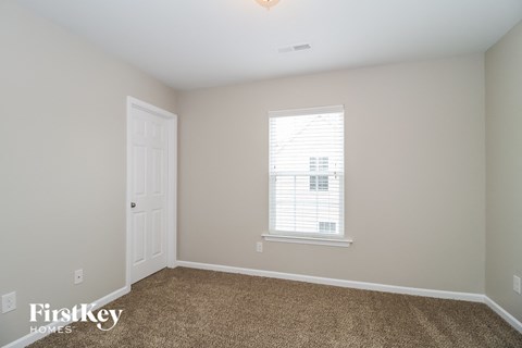 a bedroom with carpet and a door and a window
