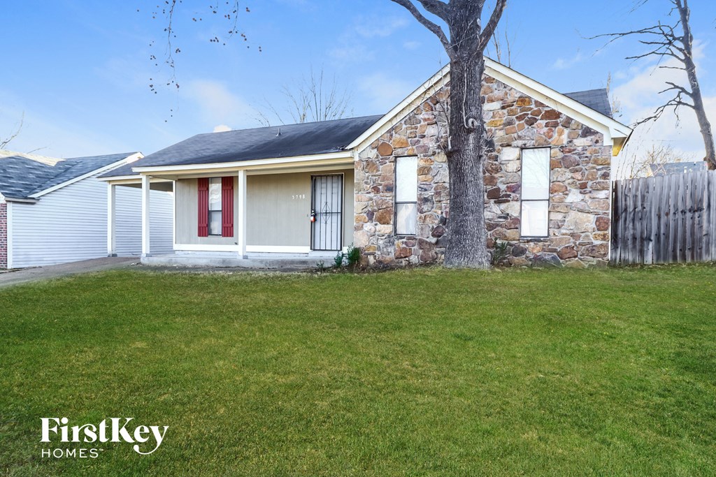 a small stone house with a yard and a tree