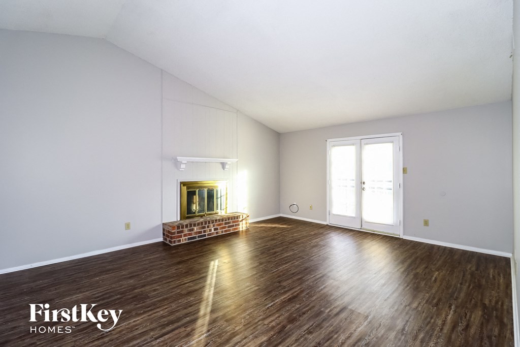 a living room with white walls and wood floors and a fireplace