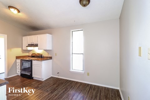 a kitchen with white cabinets and a stove and a window