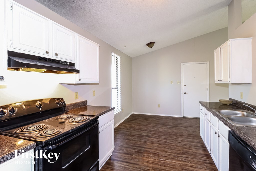 a kitchen with white cabinets and a stove and a sink