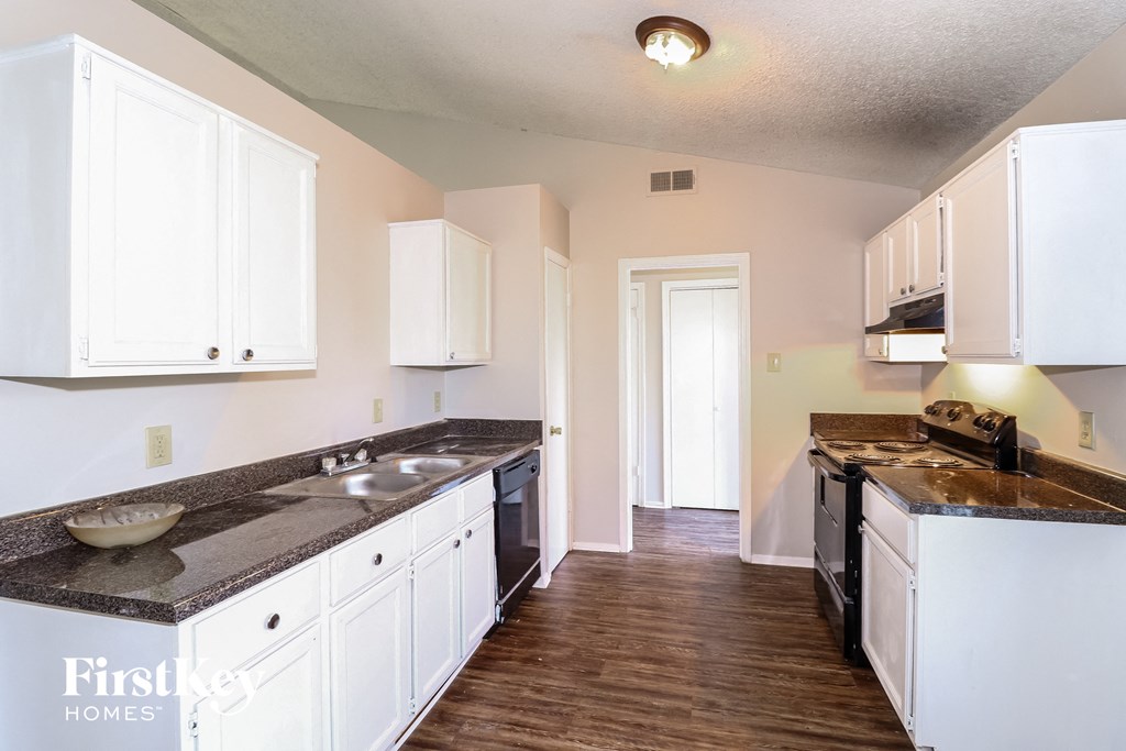 a kitchen with white cabinets and a stove and a sink