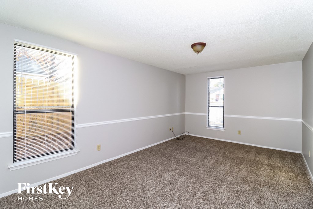 the living room of an empty house with carpet and a window