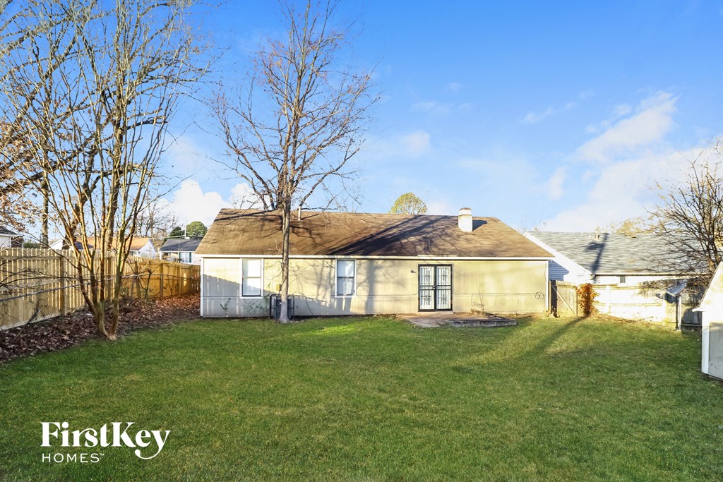 a small yellow house with a yard and a fence