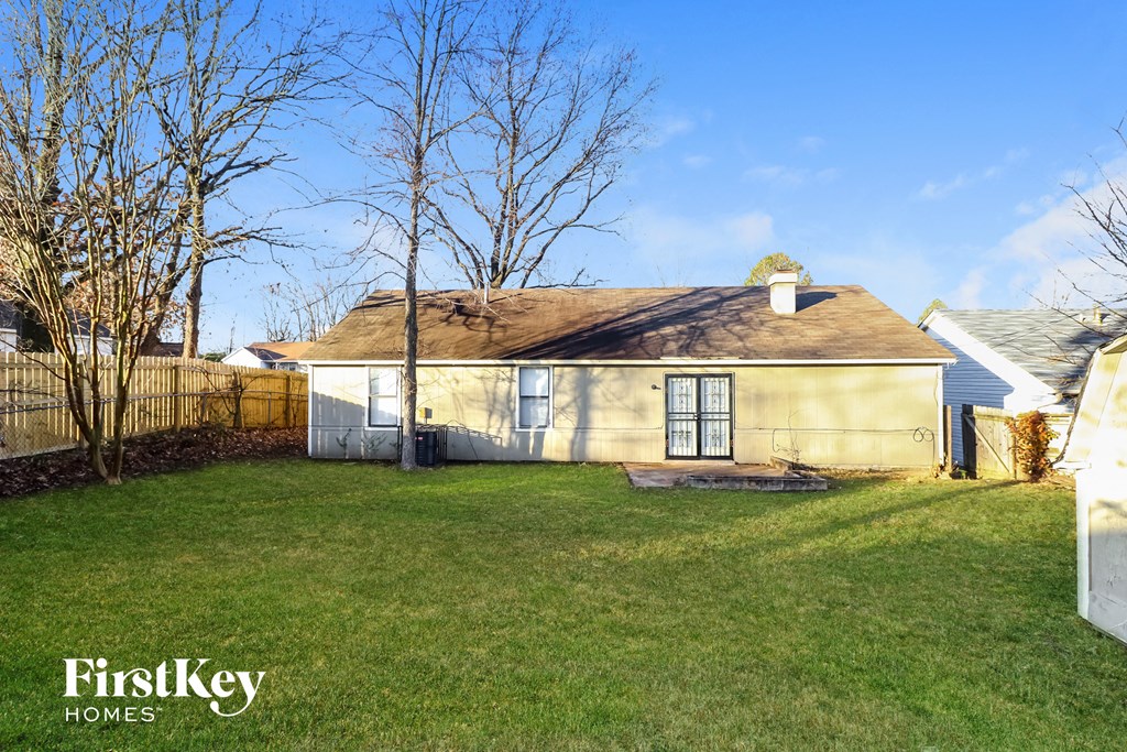 a small yellow house with a yard and a fence