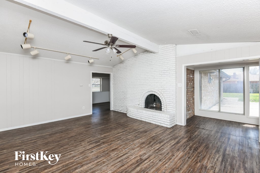 the living room of a house with a brick fireplace and wooden floors