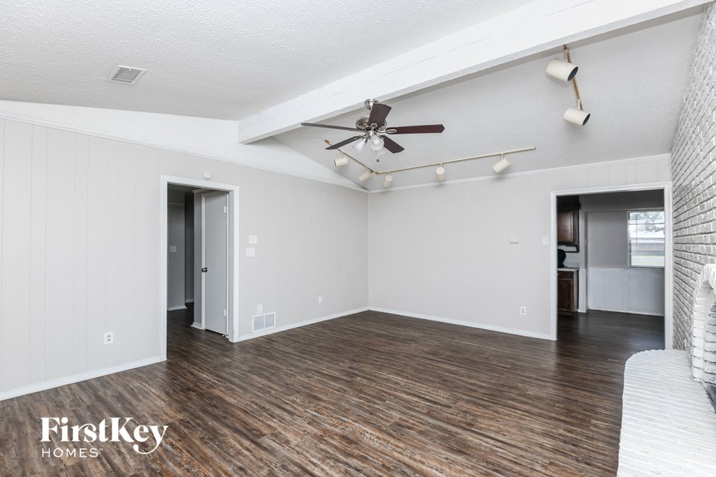an empty living room with white walls and a ceiling fan