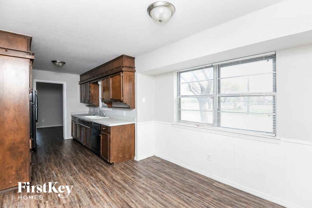 an empty kitchen with a large window and wood flooring