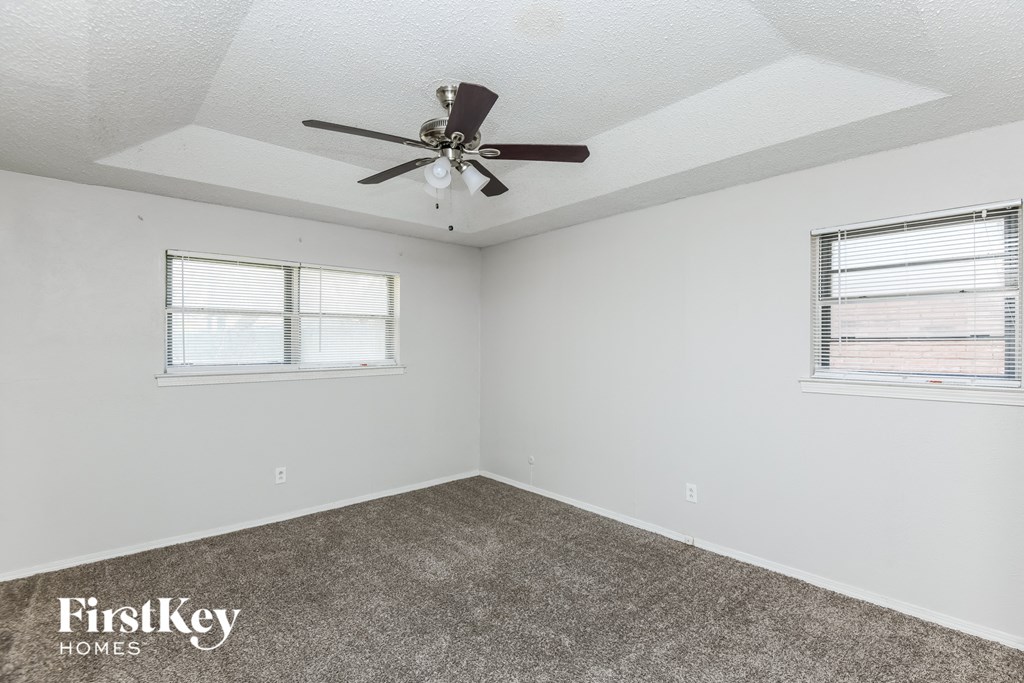 a bedroom with a ceiling fan and two windows