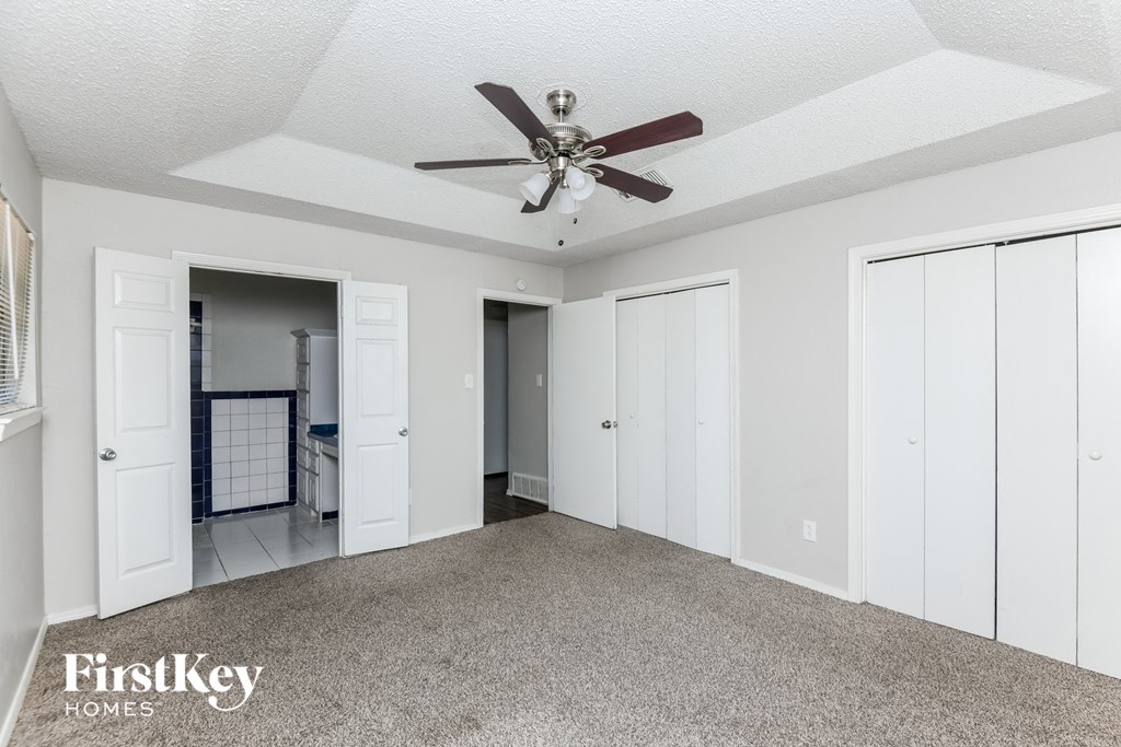a living room with a ceiling fan and white closets