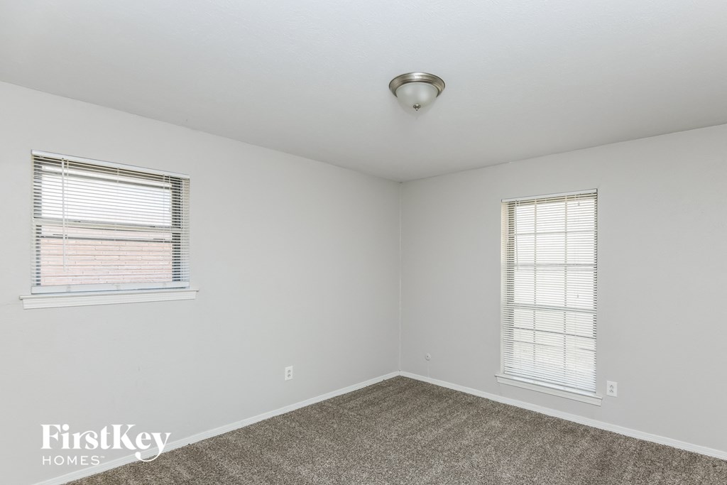 a bedroom with two windows and a carpeted floor