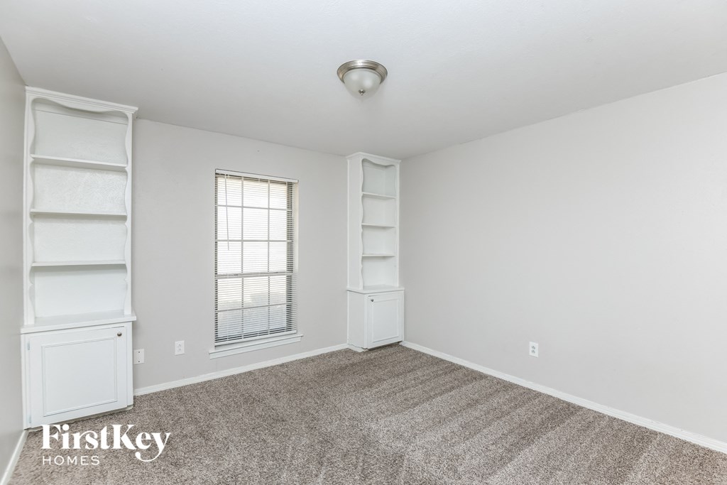 a bedroom with white shelves and carpet and a window
