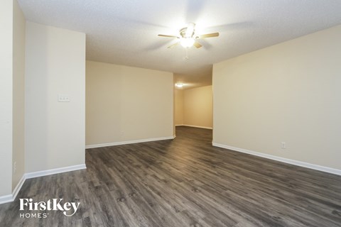 A spacious room with wooden flooring and a ceiling fan.