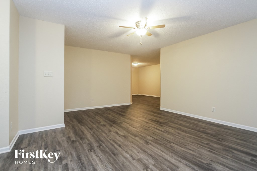 A spacious room with wooden flooring and a ceiling fan.