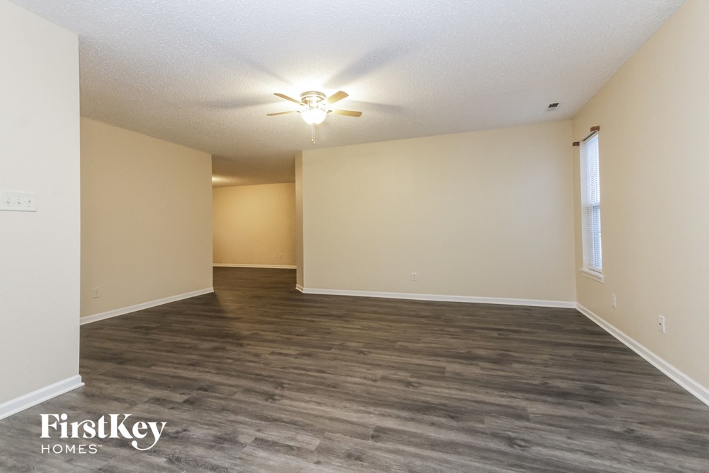 A spacious room with a ceiling fan and light fixture.
