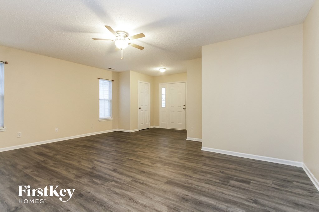 A spacious room with a ceiling fan and wooden flooring.