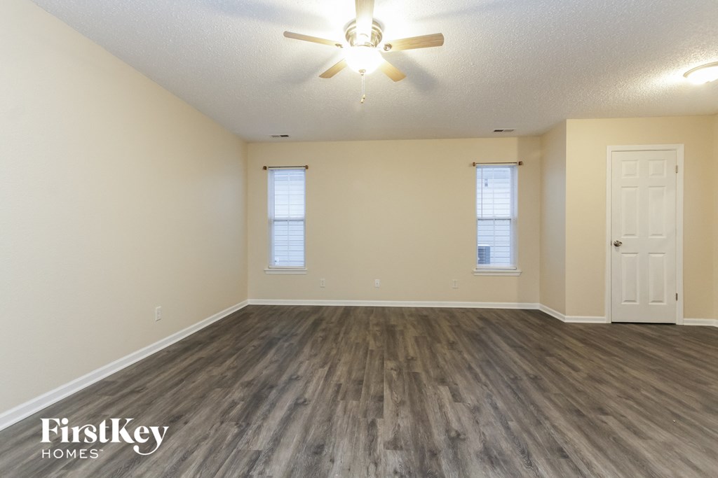 A spacious room with wooden floors and a ceiling fan.