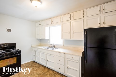 A kitchen with white cabinets and a black refrigerator.