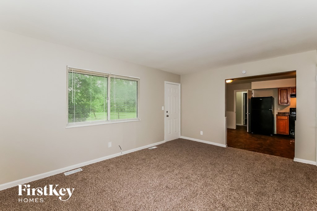A room with a carpeted floor and a window with blinds.
