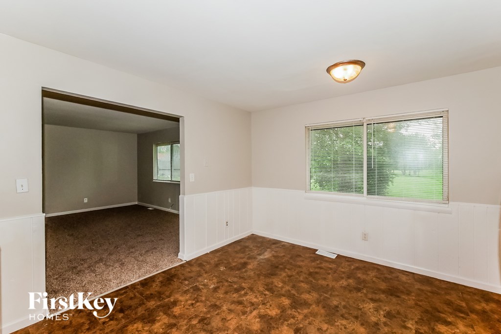 A room with a brown carpet and a window with blinds.
