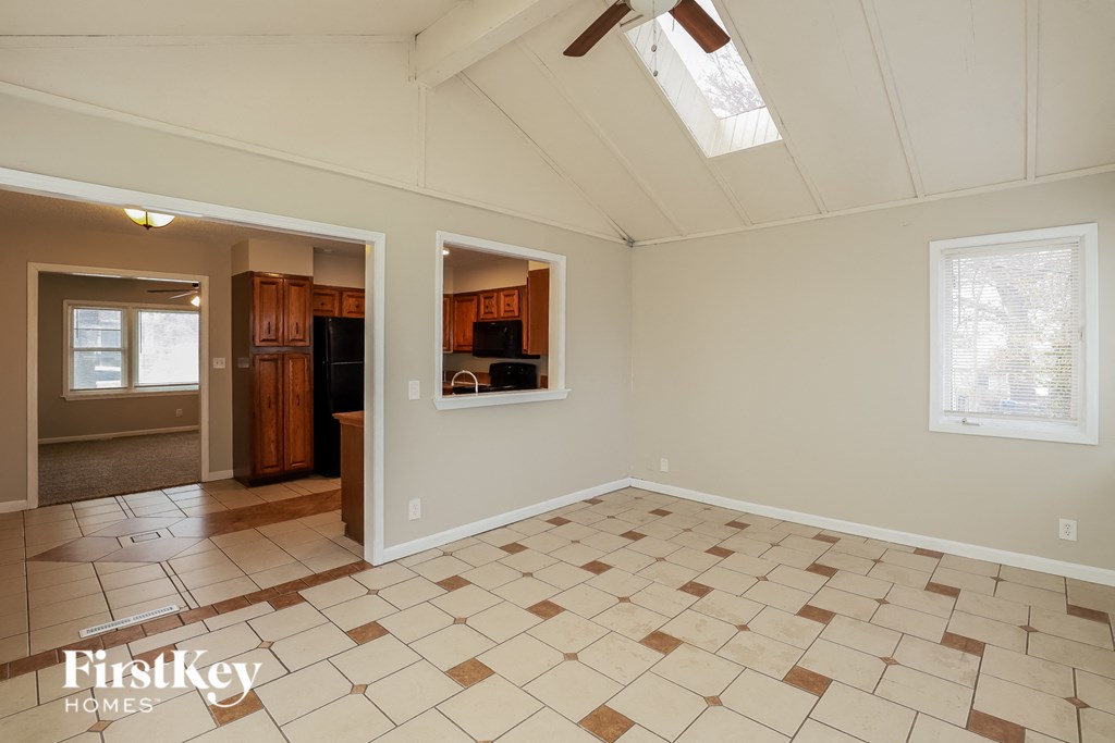 A spacious room with tile flooring and a skylight.