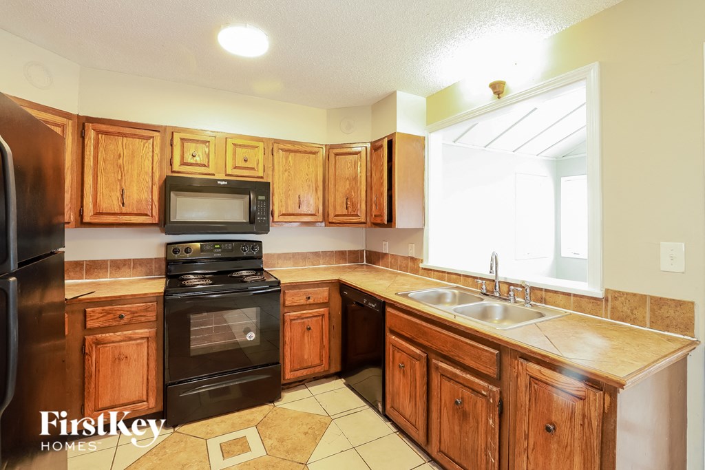 A kitchen with wooden cabinets and a black stove top oven.