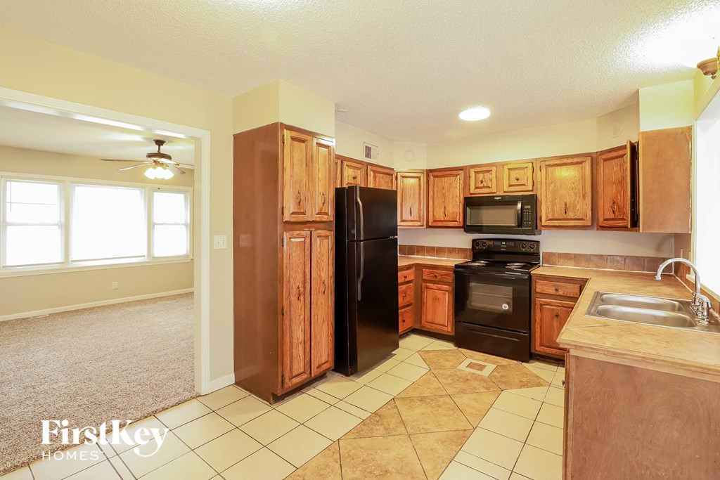 A kitchen with wooden cabinets and a black refrigerator.