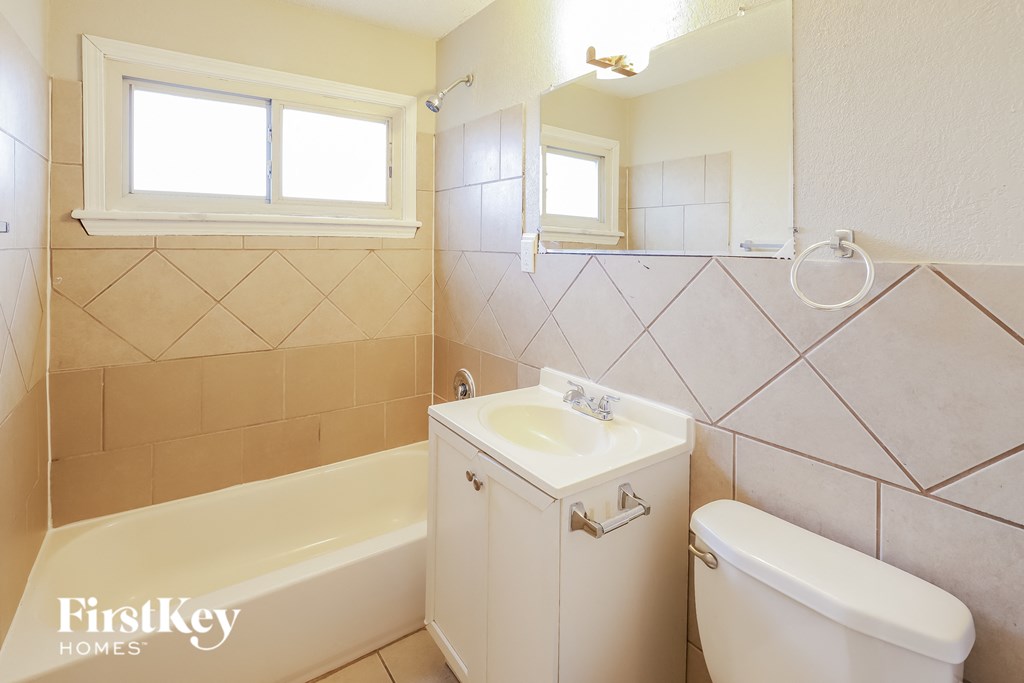 A white bathroom with a tub, sink and toilet.
