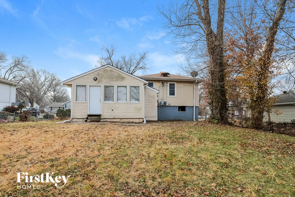 A small house with a porch and a tree in front of it.