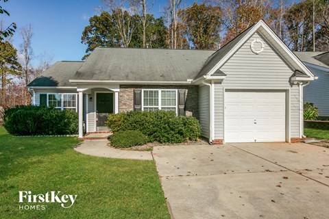 a small blue house with a driveway and a white garage door