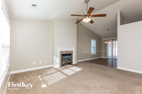 an empty living room with a fireplace and a ceiling fan