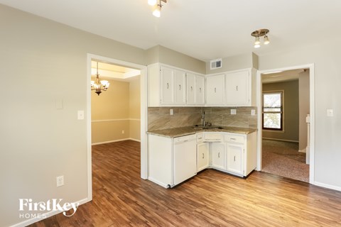 A kitchen with white cabinets and a wooden floor.