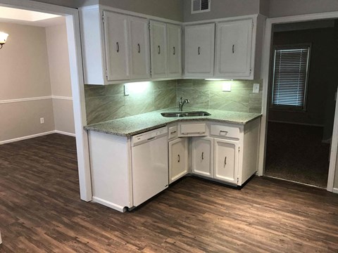 A kitchen with white cabinets and a granite countertop.