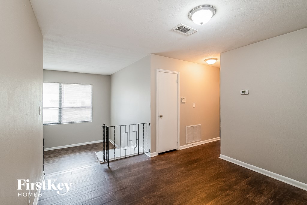 an empty living room with a staircase and a window