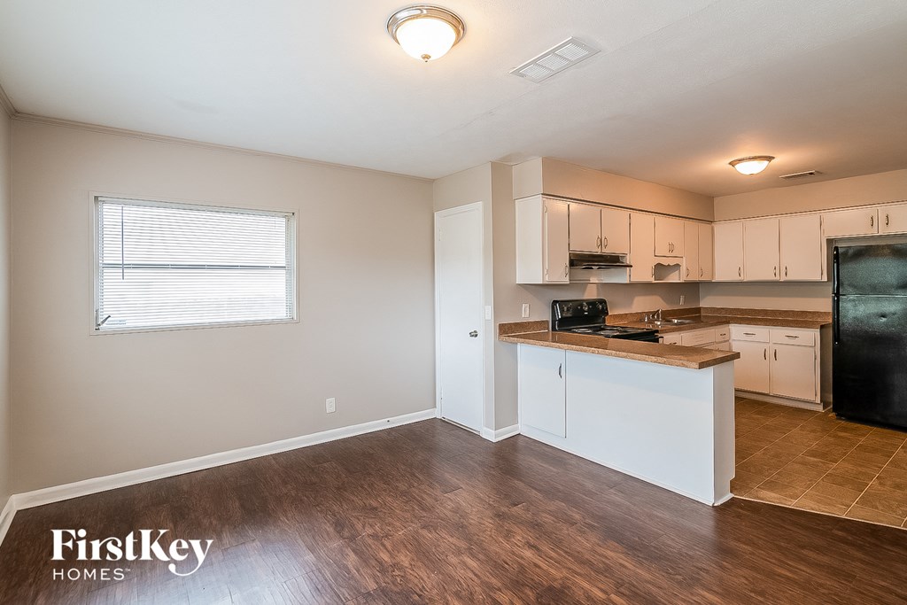 a kitchen with white cabinets and a black refrigerator