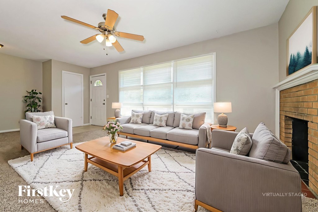 A living room with a grey couch, a wooden coffee table, and a ceiling fan.