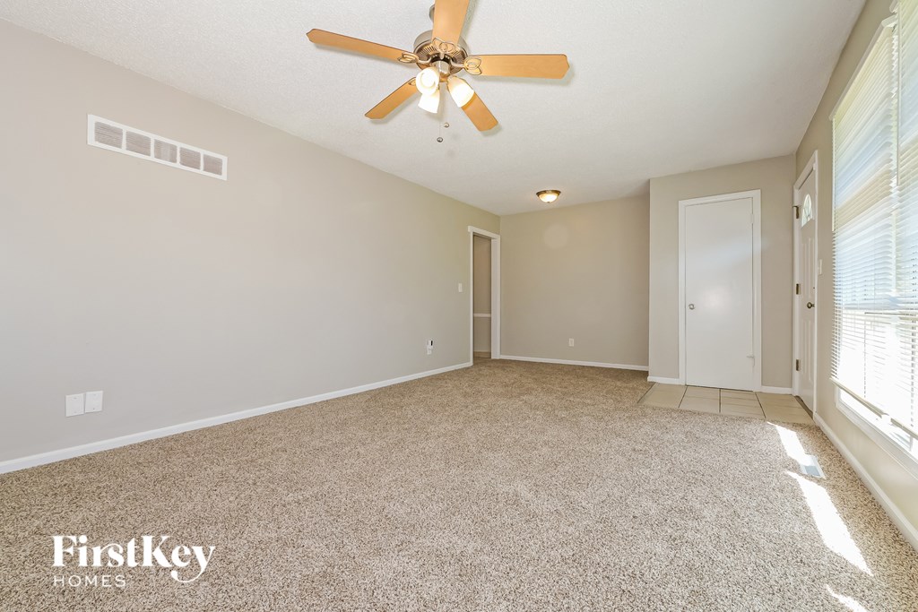 A spacious room with a ceiling fan and carpeted floor.
