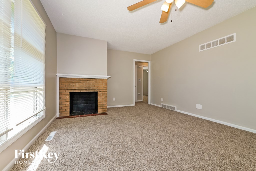 A spacious living room with a fireplace and a ceiling fan.