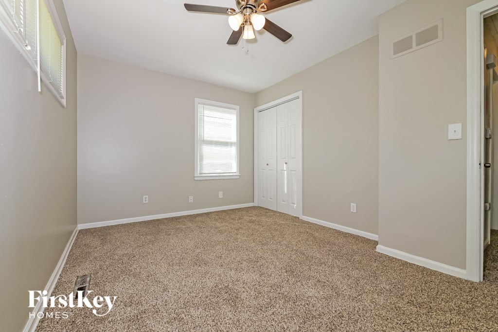 A room with a carpeted floor and a ceiling fan.