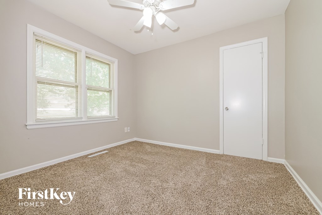 A room with a carpeted floor, a ceiling fan, and a window with blinds.