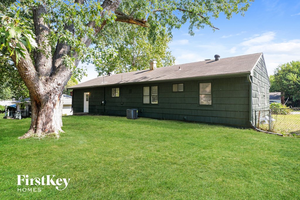 A green house with a tree in front of it.
