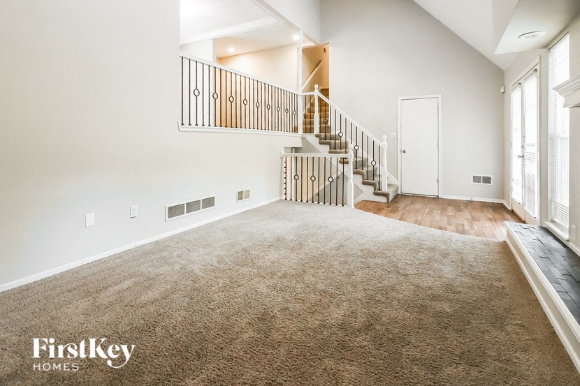 an empty living room with a staircase and a carpeted floor
