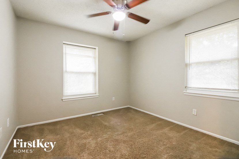 an empty room with two windows and a ceiling fan