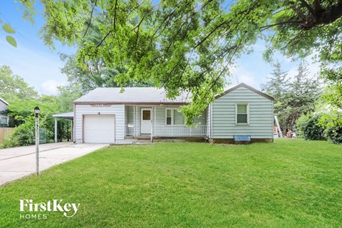 a small white house with a yard and a driveway