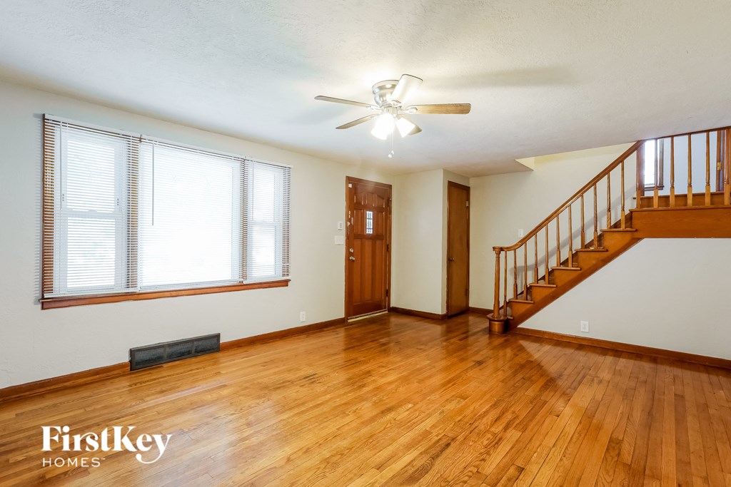 an empty living room with wood flooring and a staircase