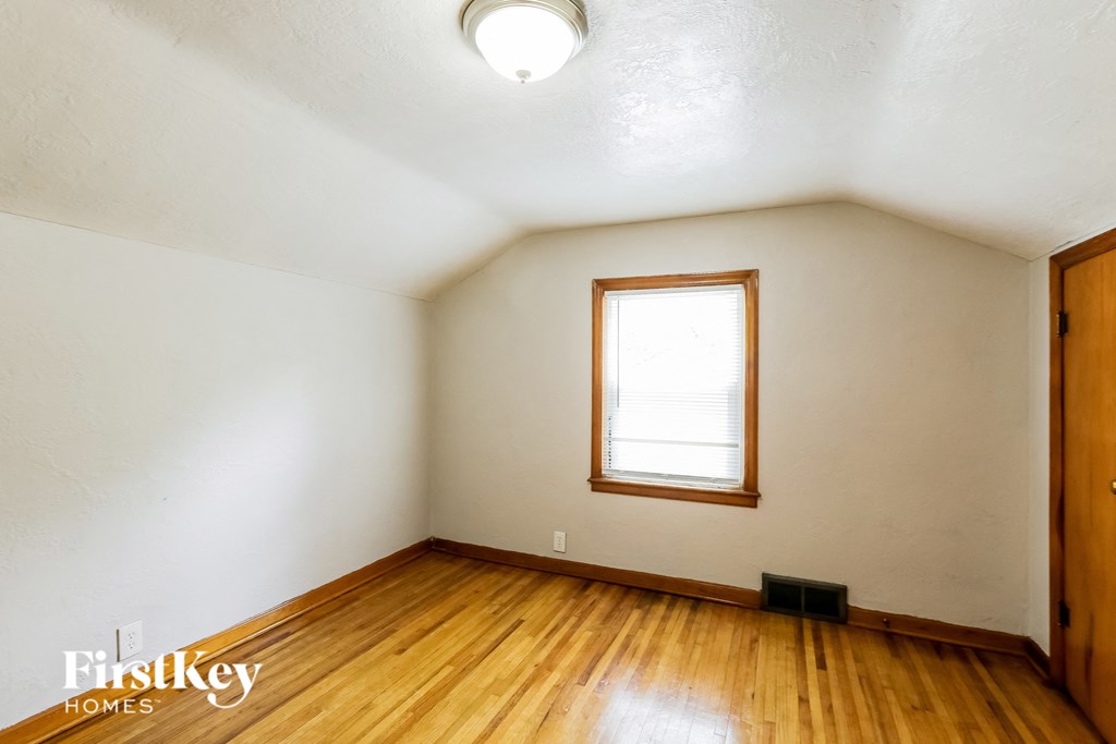 the bedroom of an attic with wood floors and a window