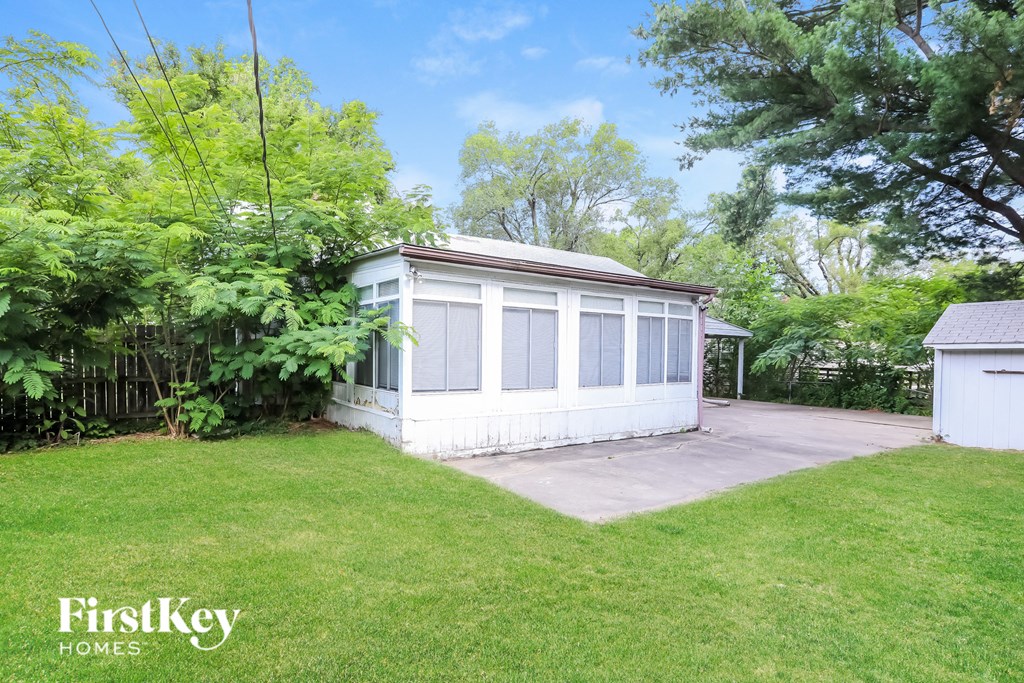 a small white house with a yard and a driveway